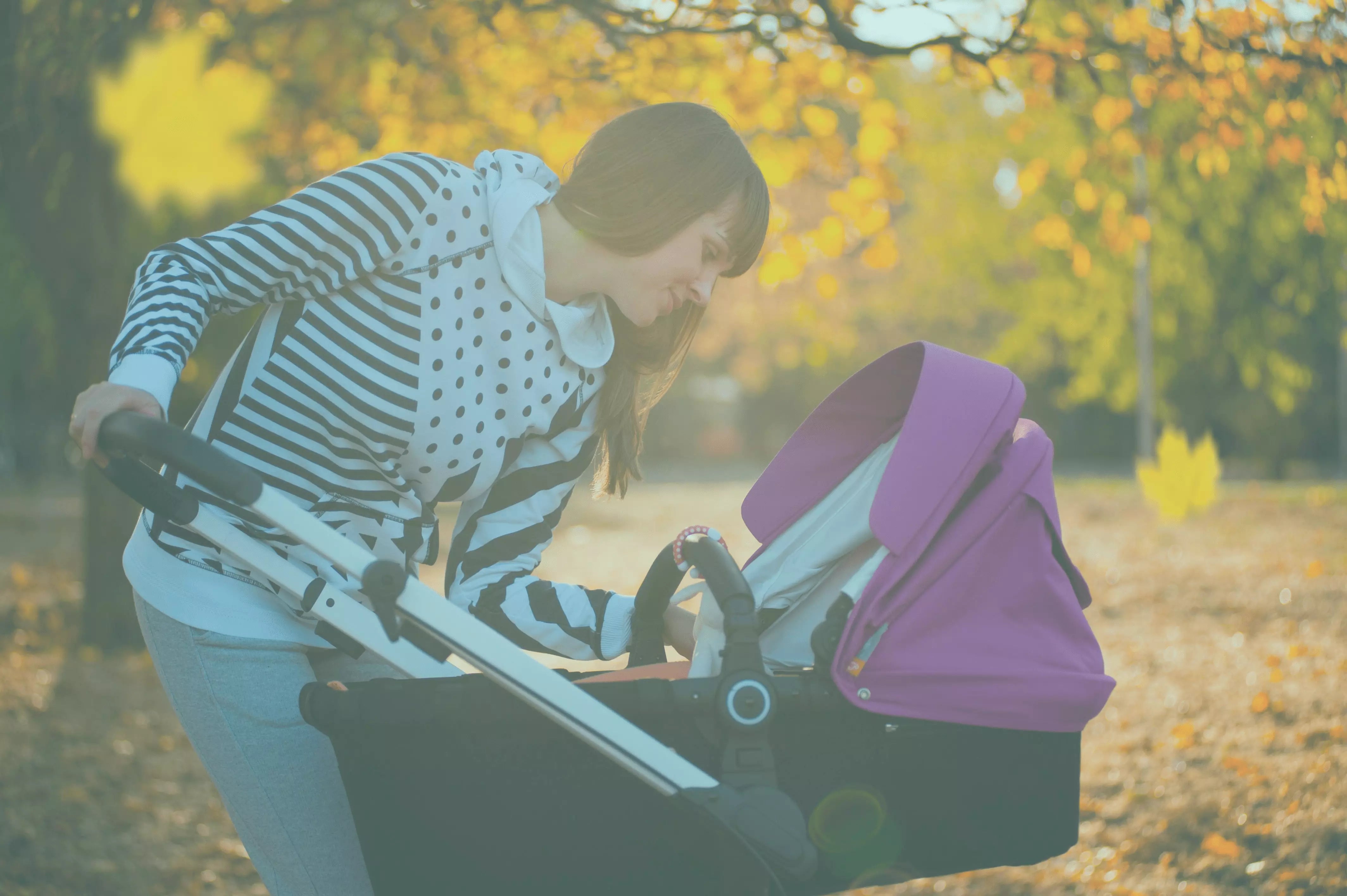 Mama paseando a su bebe en carriola tipo bambineto en un parque